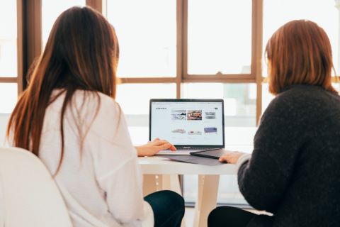 Two women looking in to laptop