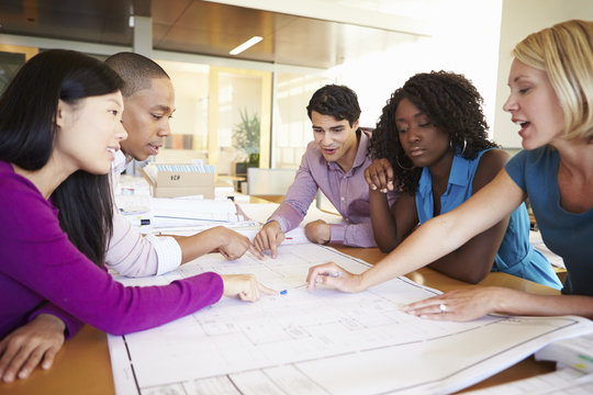 Group Of Architects Discussing Plans In Office