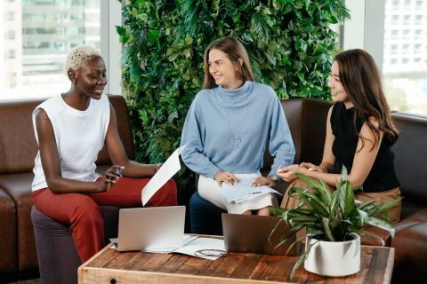 Three people sitting and smiling at each other in an office setting