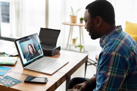 Person looking at and talking to colleague on their laptop